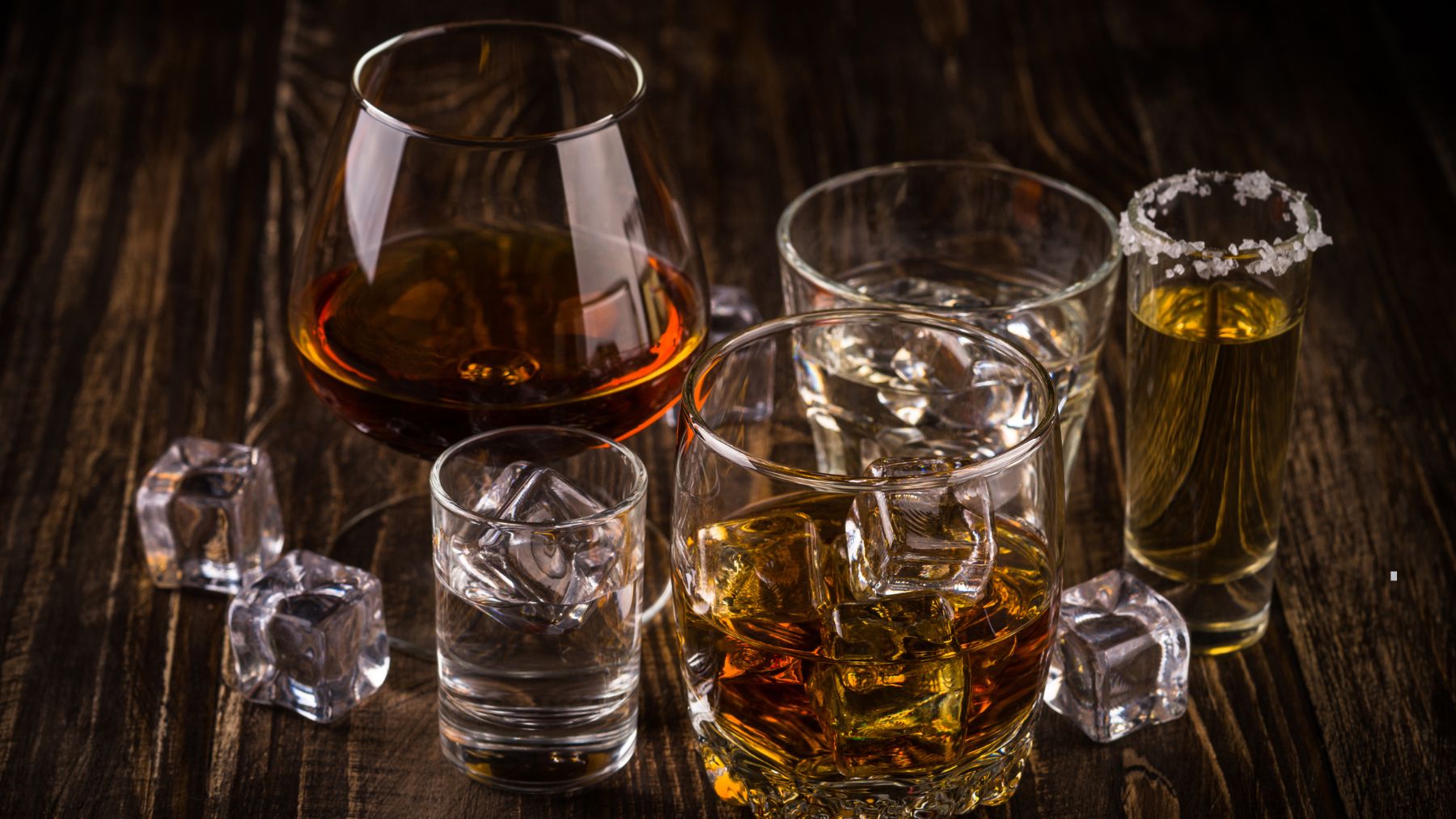 Bebidas alcohólicas servidas en distintos vasos sobre una mesa de madera