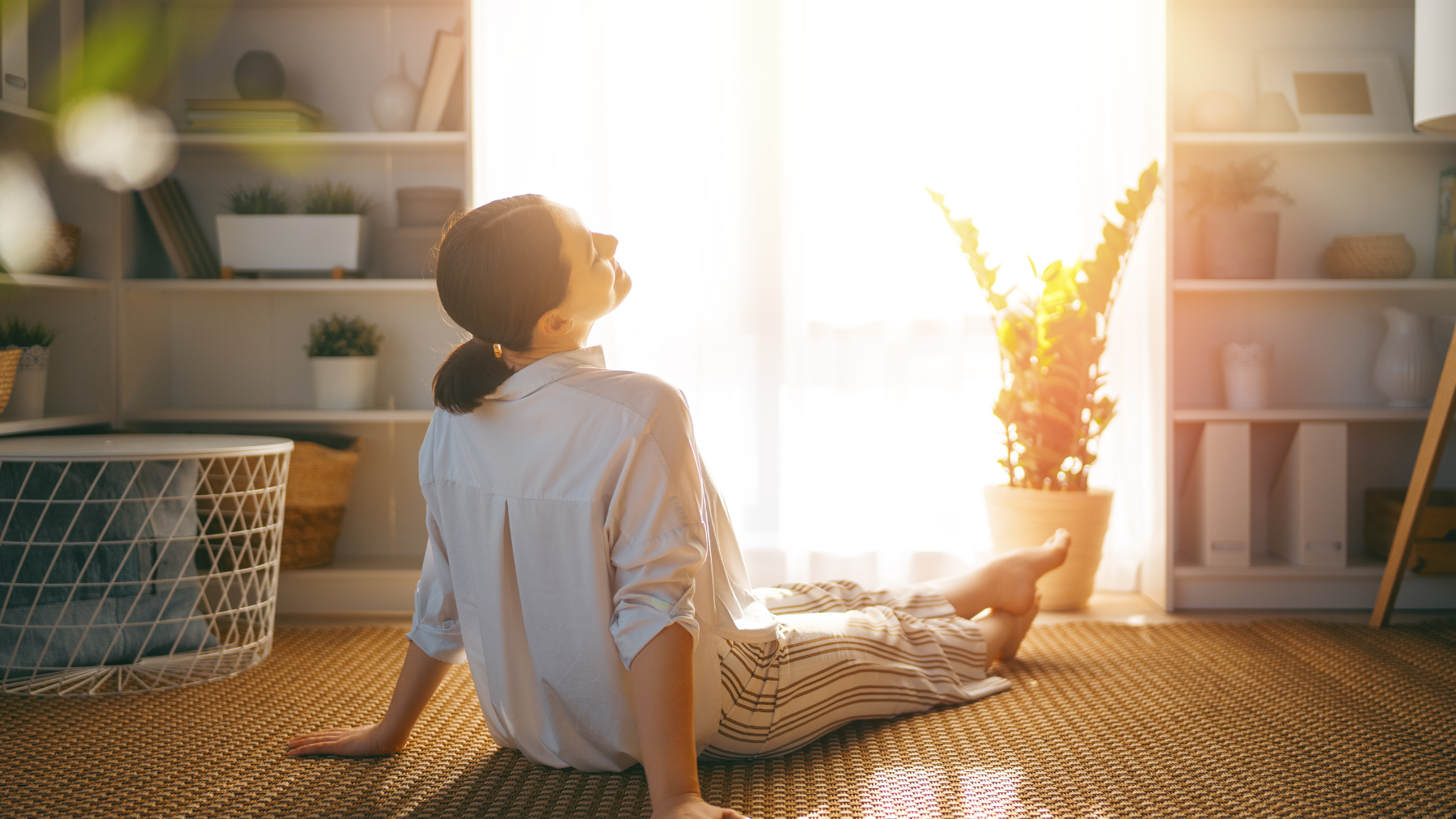 Mujer sentada en casa mirando la luz natural en un momento de descanso sin pantallas.