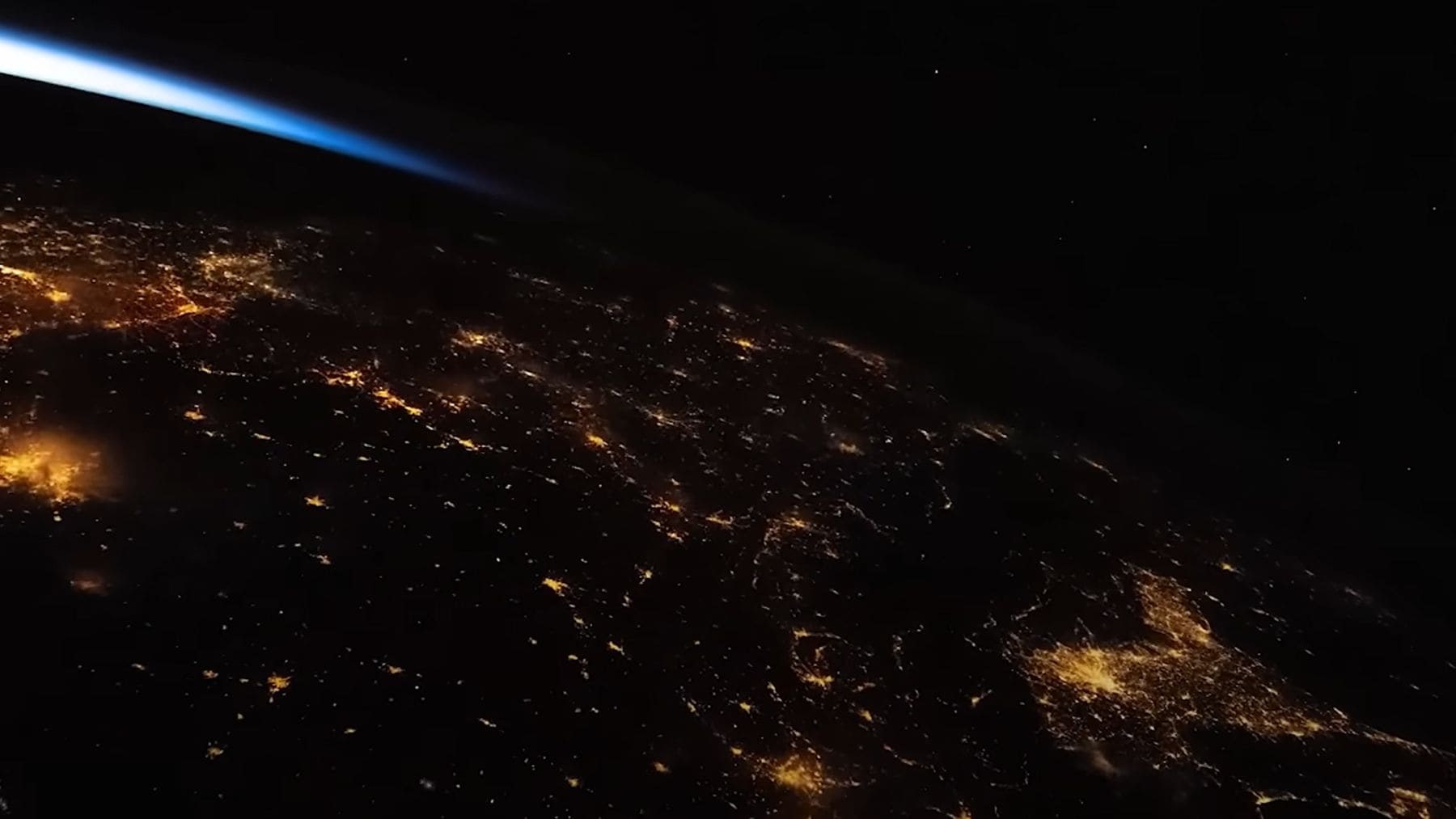 Vista de la Tierra de noche desde la Estación Espacial Internacional con la atmósfera iluminada.