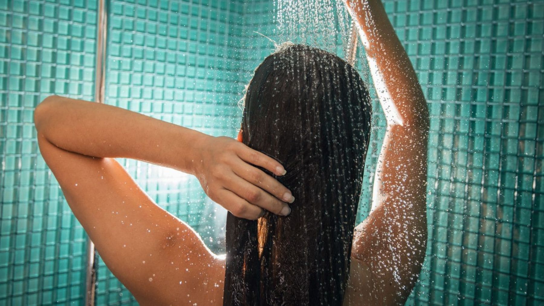 Mujer duchándose por la noche con agua templada, hábito vinculado por la psicología al bienestar y mejor descanso.