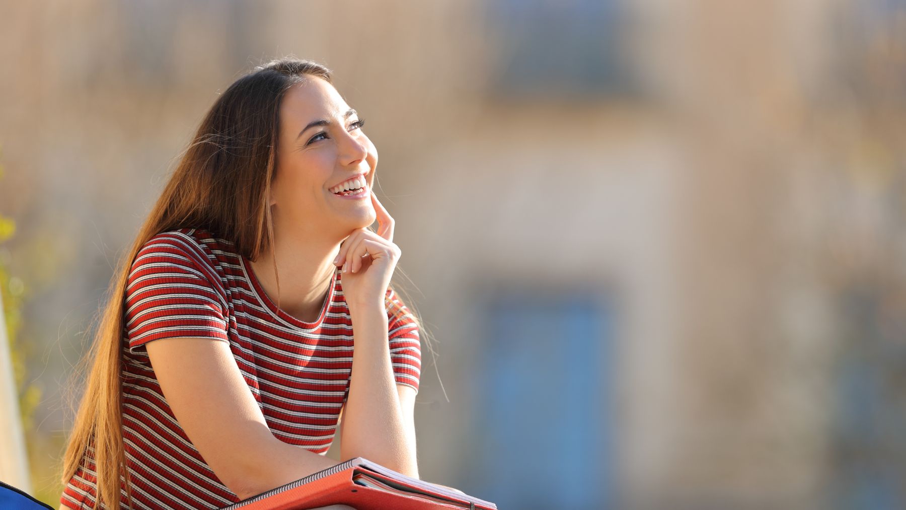 Mujer sonriendo y pensando en voz alta al aire libre, ejemplo de autodiálogo positivo según la psicología.