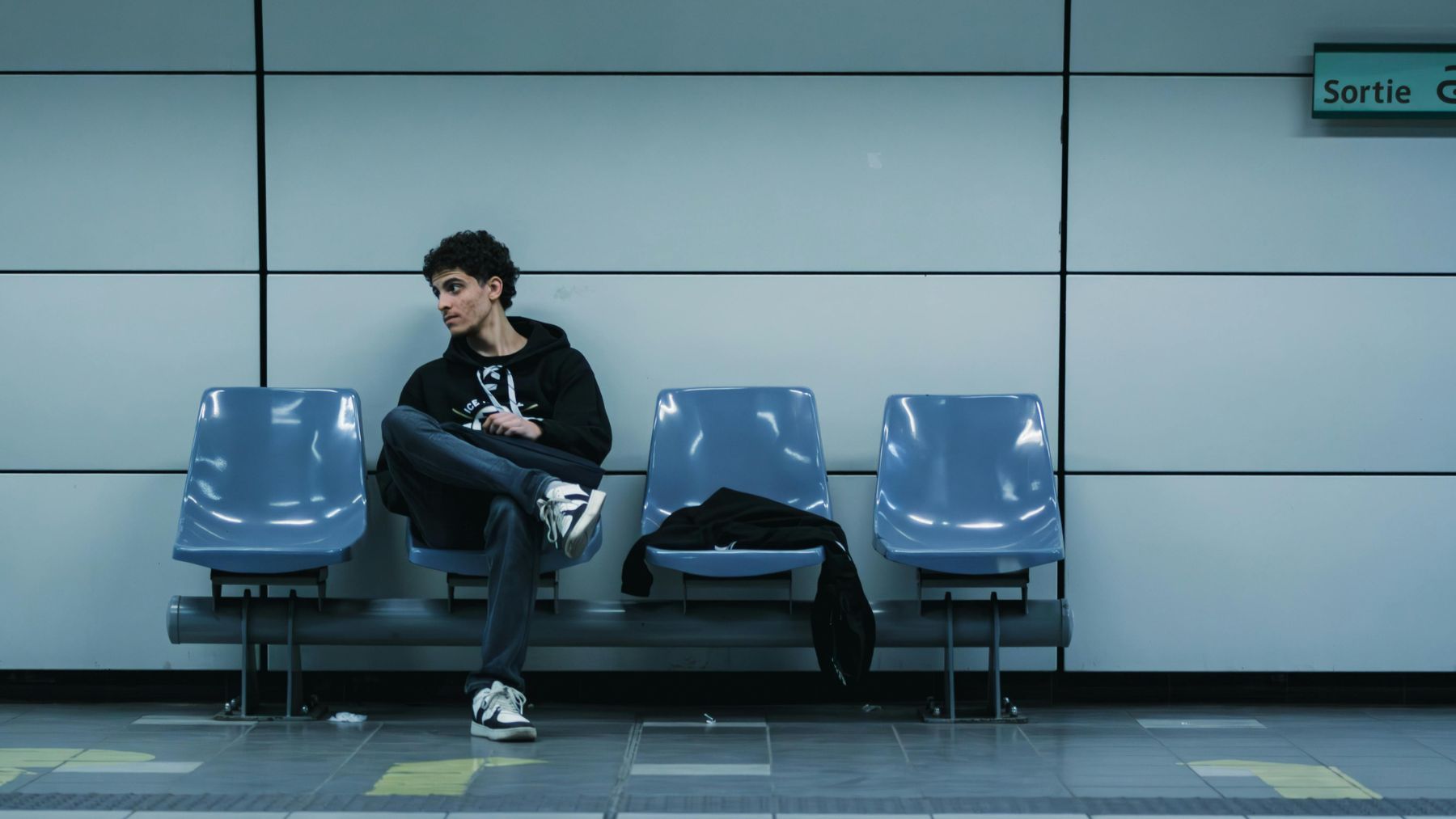 persona esperando sentada sola en una sala antes de una cita, ejemplo de puntualidad y llegar antes según la psicología.