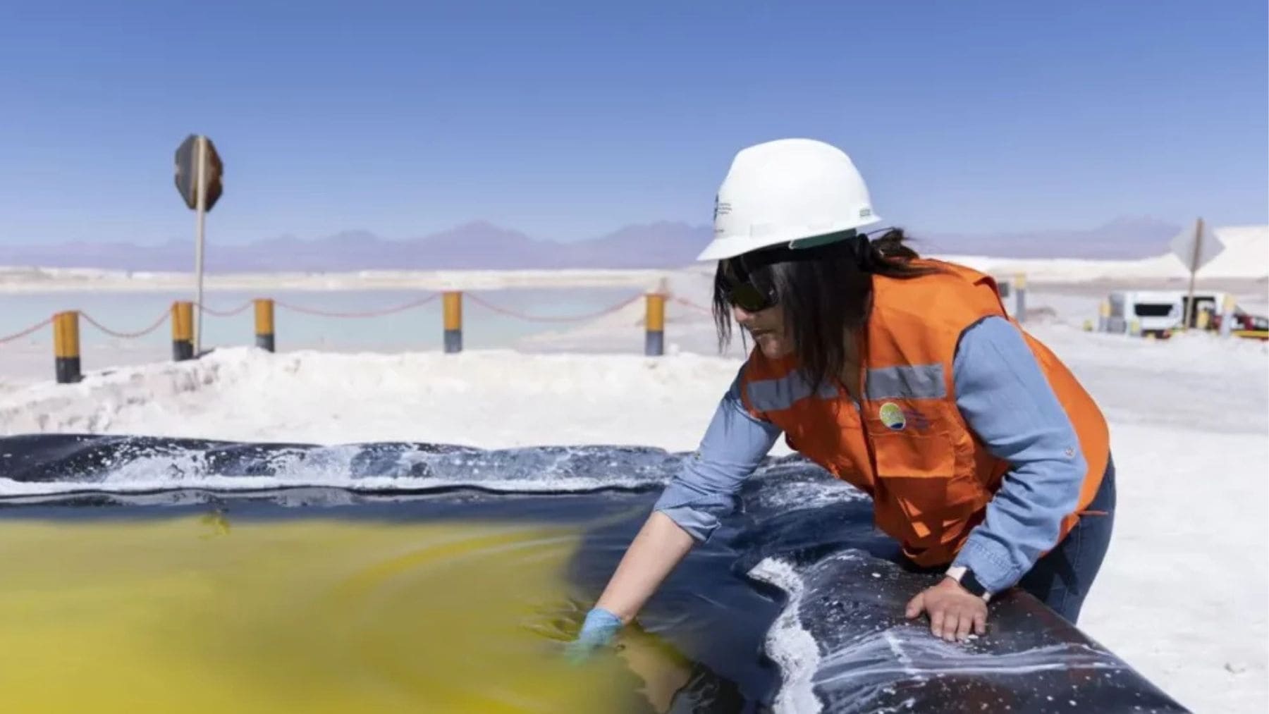 Operaria manipulando agua en balsa de minería de litio en un proyecto industrial vinculado a tierras raras.