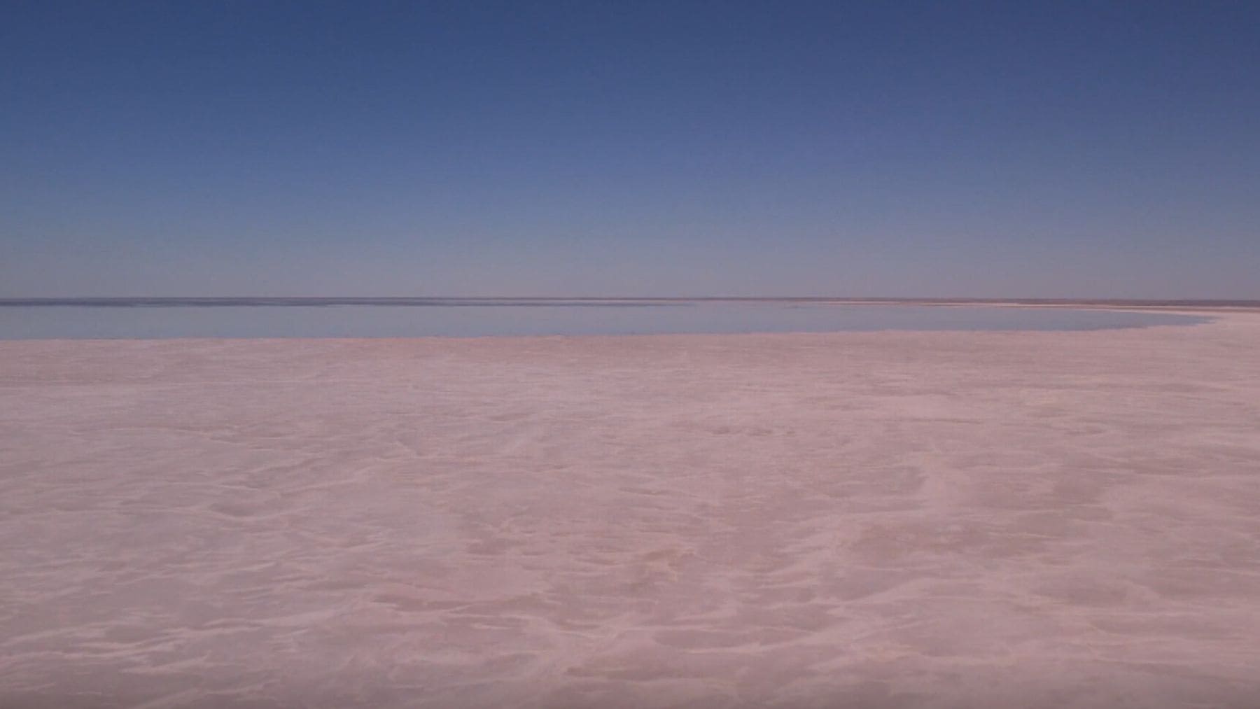 Lago Eyre seco en Australia con agua en el horizonte en pleno desierto árido.