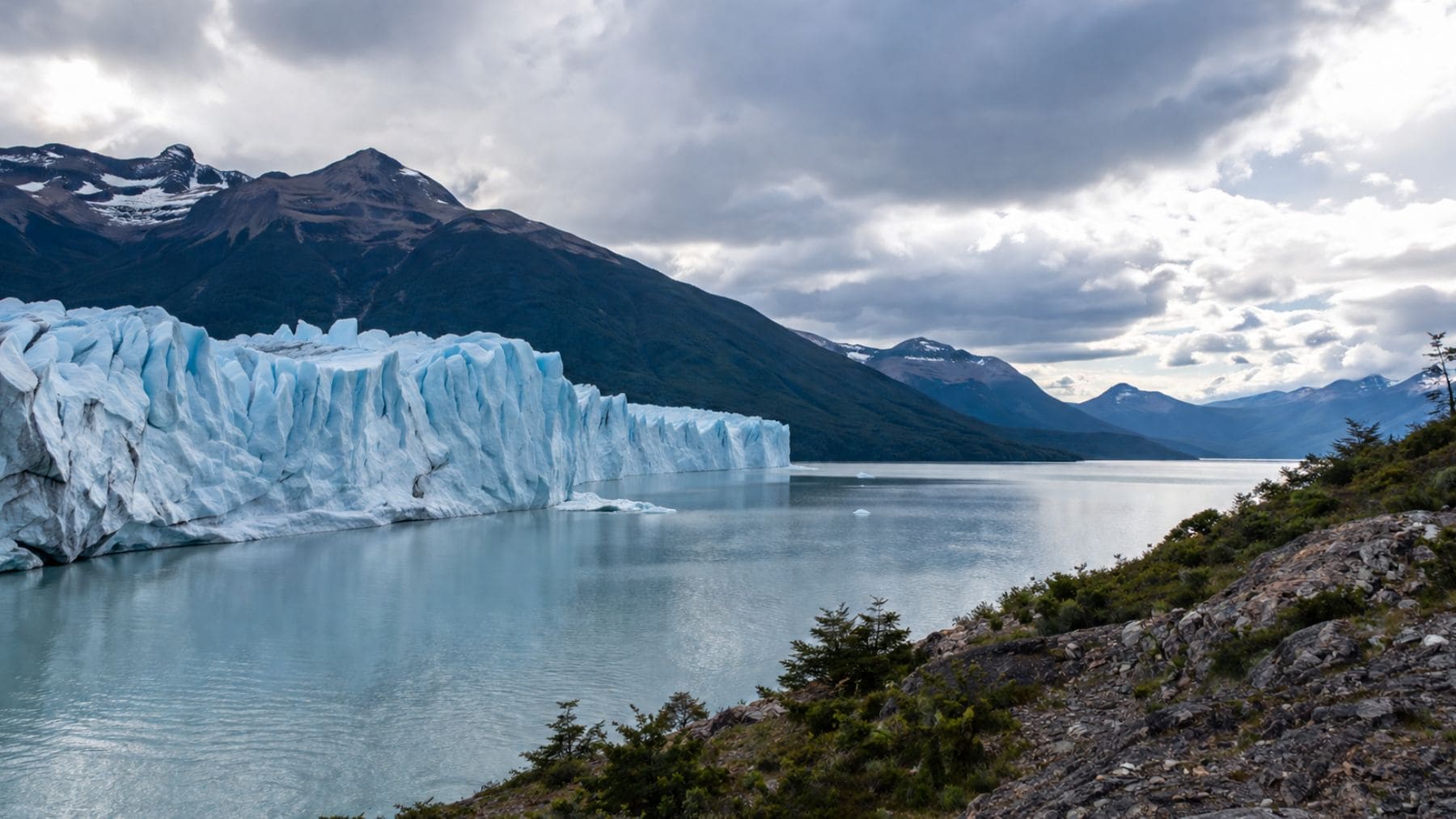 Glaciar en retroceso junto a un lago en plena crisis climática, reflejo del impacto del Antropoceno en la Tierra.
