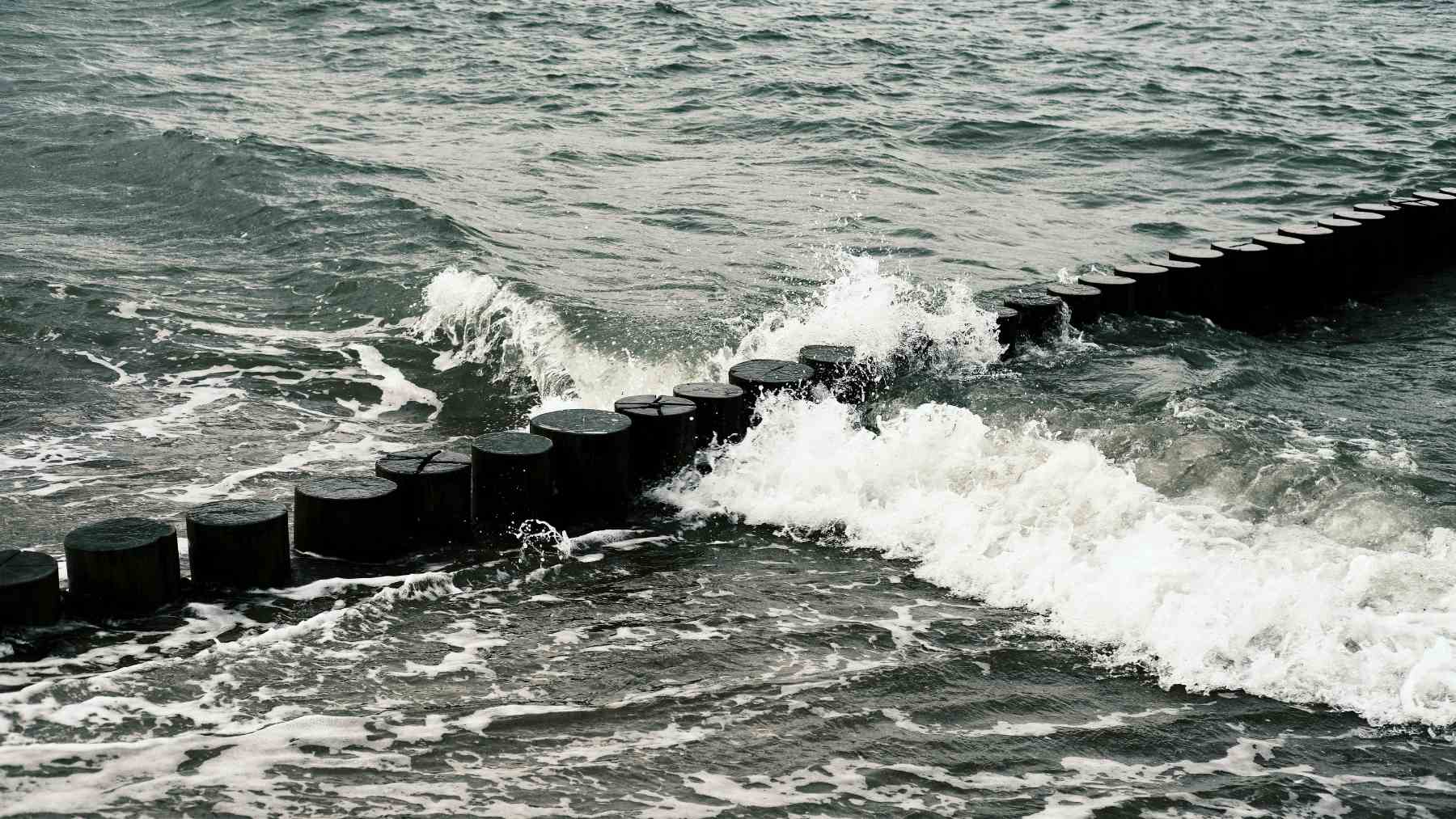 Olas del mar golpeando estructura costera, representación del origen del agua usada en sistemas navales de vapor.