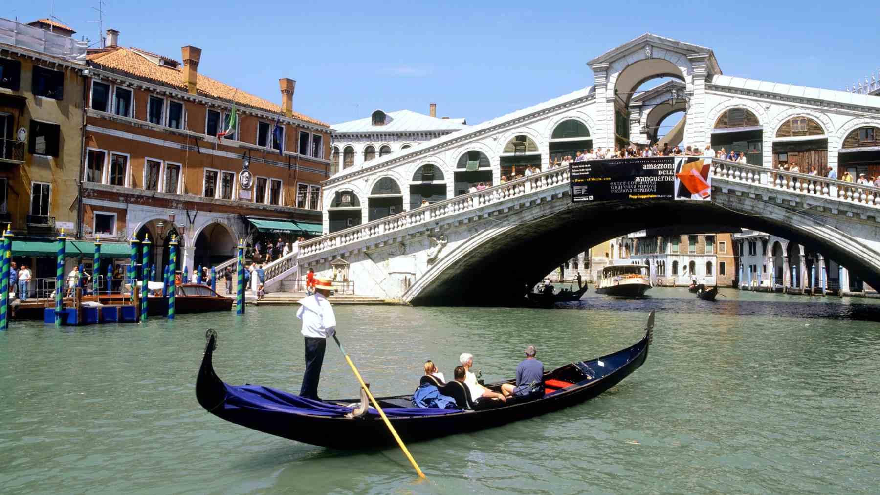 Góndola pasando bajo el puente de Rialto en Venecia, ciudad amenazada por el hundimiento y la subida del nivel del mar.