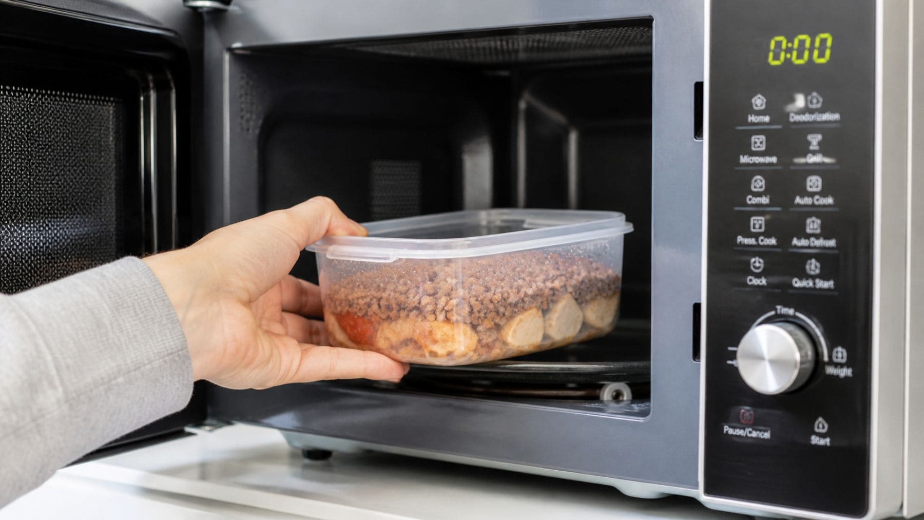 Recipiente de plástico calentándose en microondas con comida en su interior, asociado a liberación de sustancias químicas.