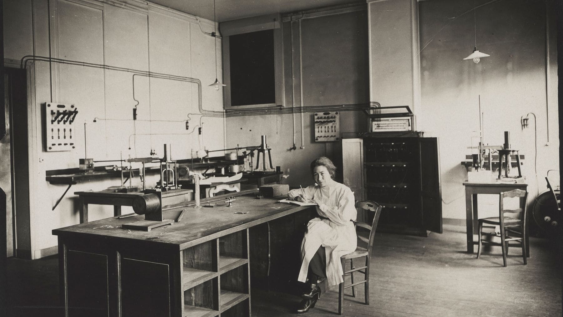 Marie Curie trabajando en su laboratorio científico en una fotografía histórica en blanco y negro.