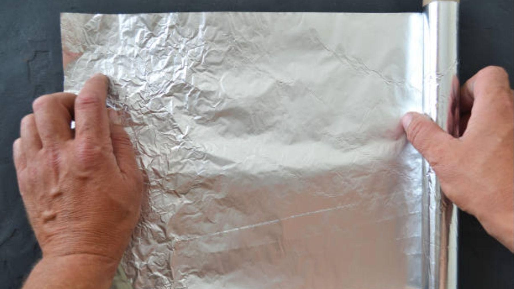 Persona realizando la prueba del papel de aluminio en una pared para detectar humedades y problemas de aislamiento.