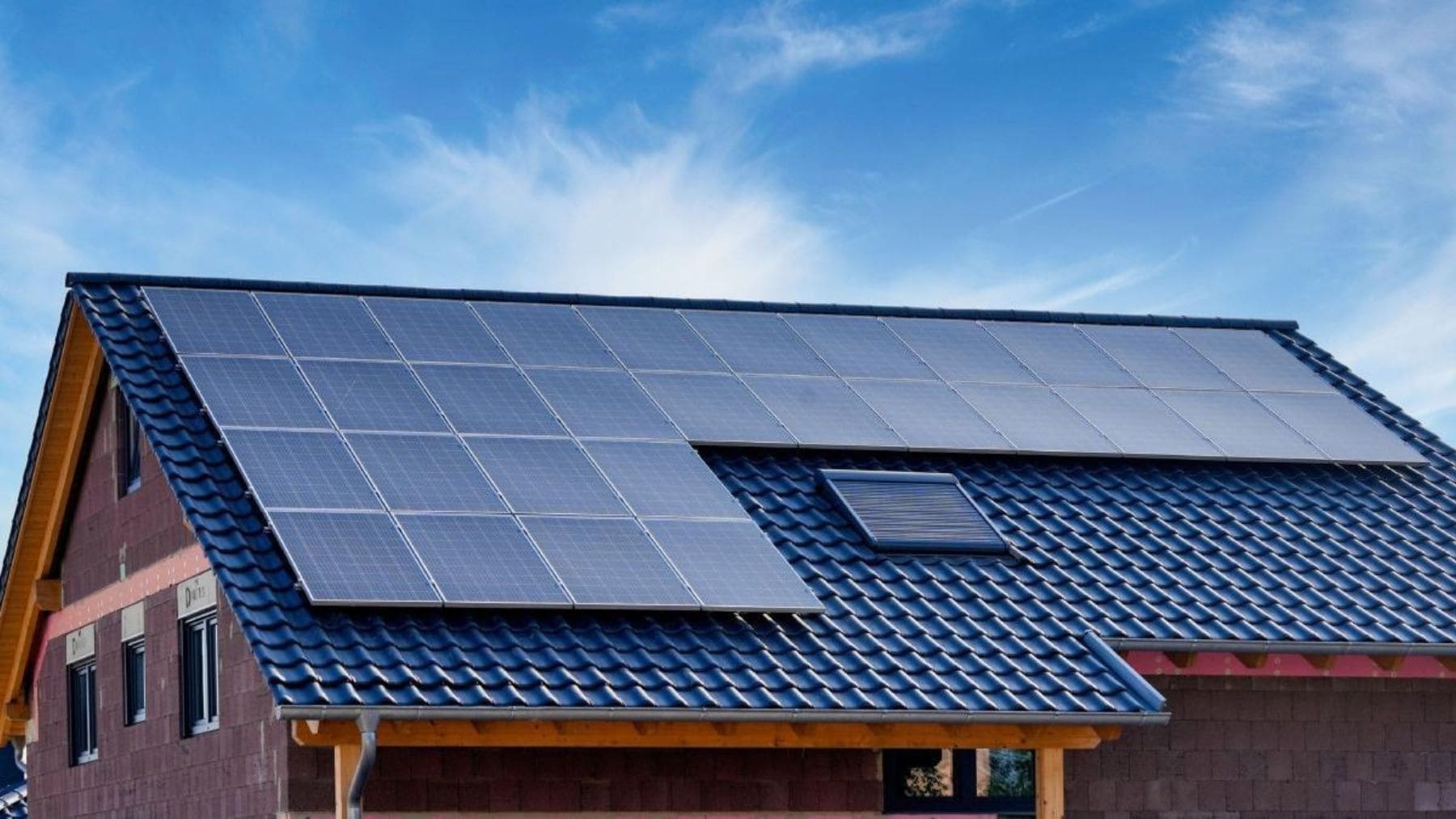 Casa con paneles solares en el tejado y sistema de autoconsumo con baterías para reducir la factura de la luz.