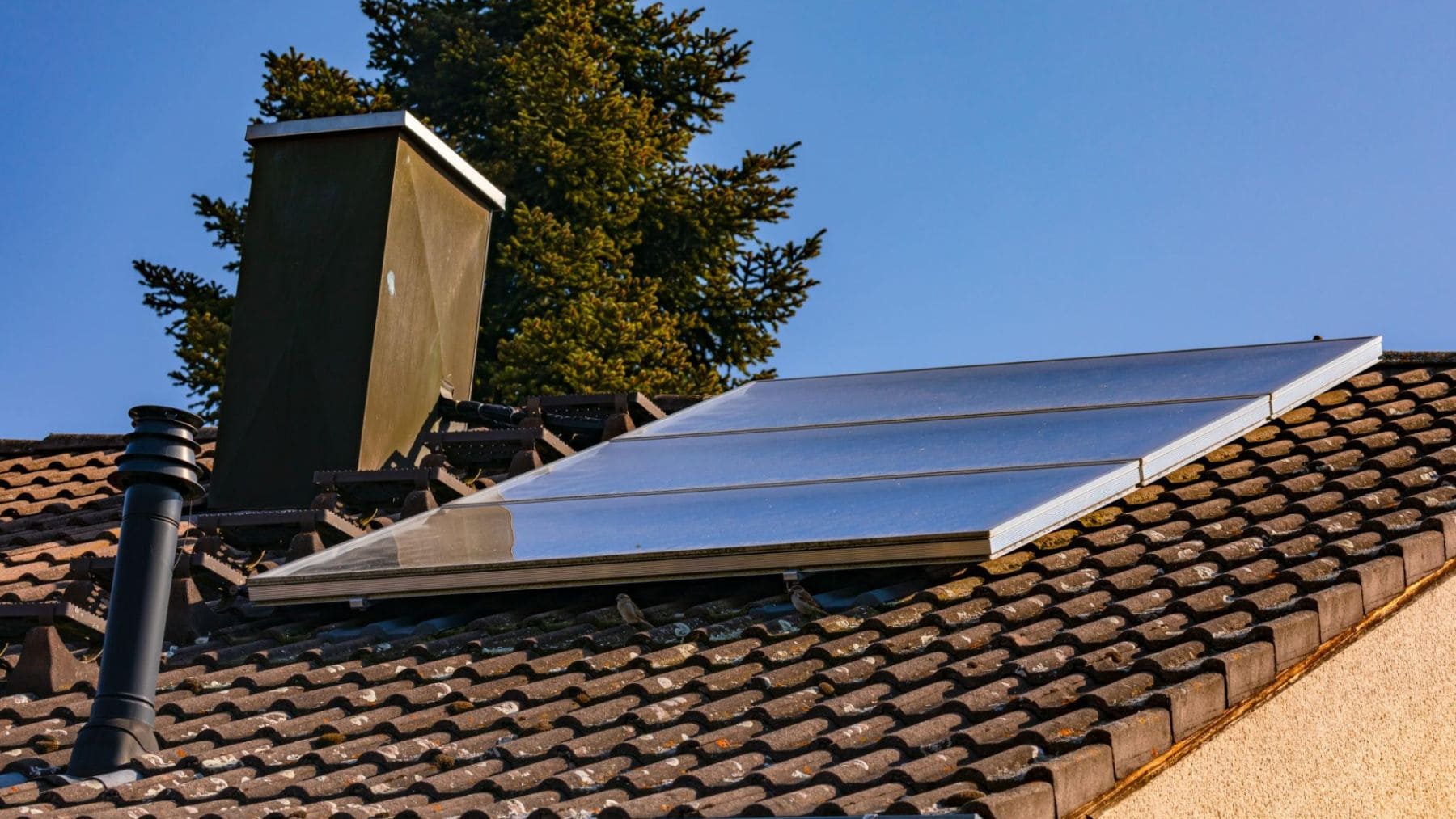 Colectores solares térmicos instalados en el tejado de una vivienda para producir agua caliente y apoyar la calefacción.