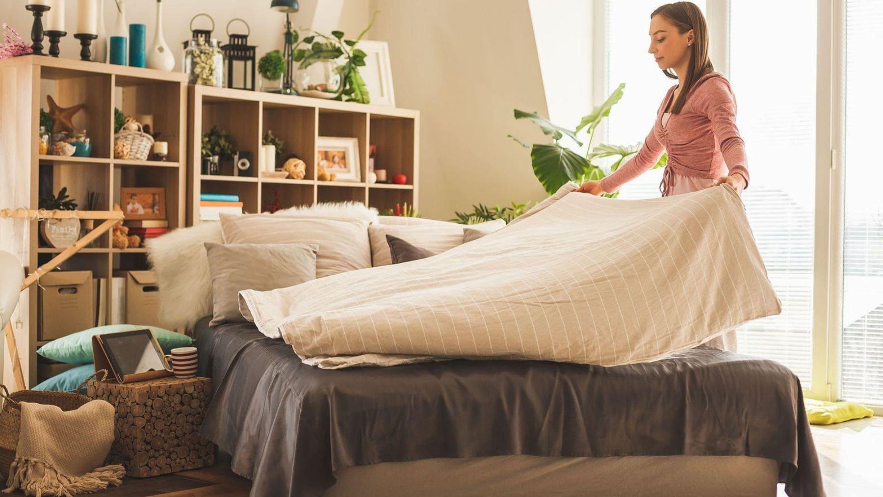 Mujer haciendo la cama en un dormitorio ordenado como ejemplo de cómo el orden en casa ayuda a reducir la ansiedad según la psicología.