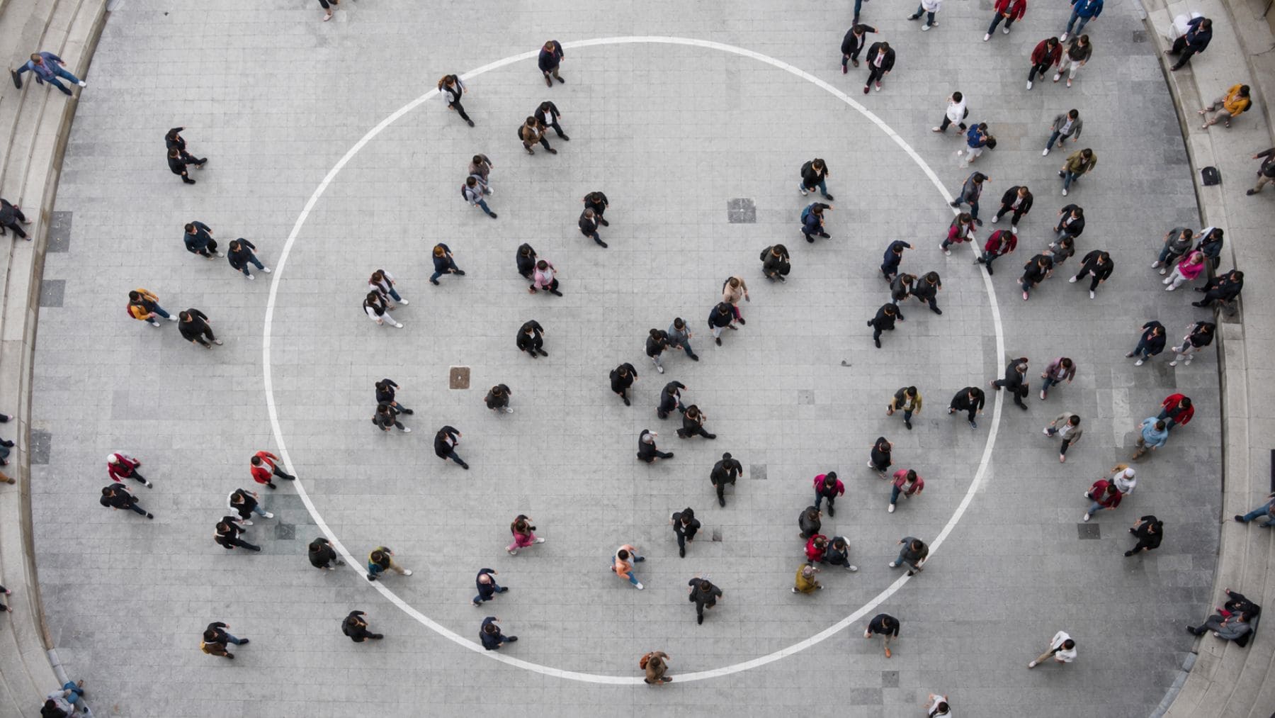 Vista aérea de un grupo de personas caminando en un espacio abierto, ilustrando el descubrimiento de científicos de Navarra sobre la tendencia humana a girar hacia la izquierda.
