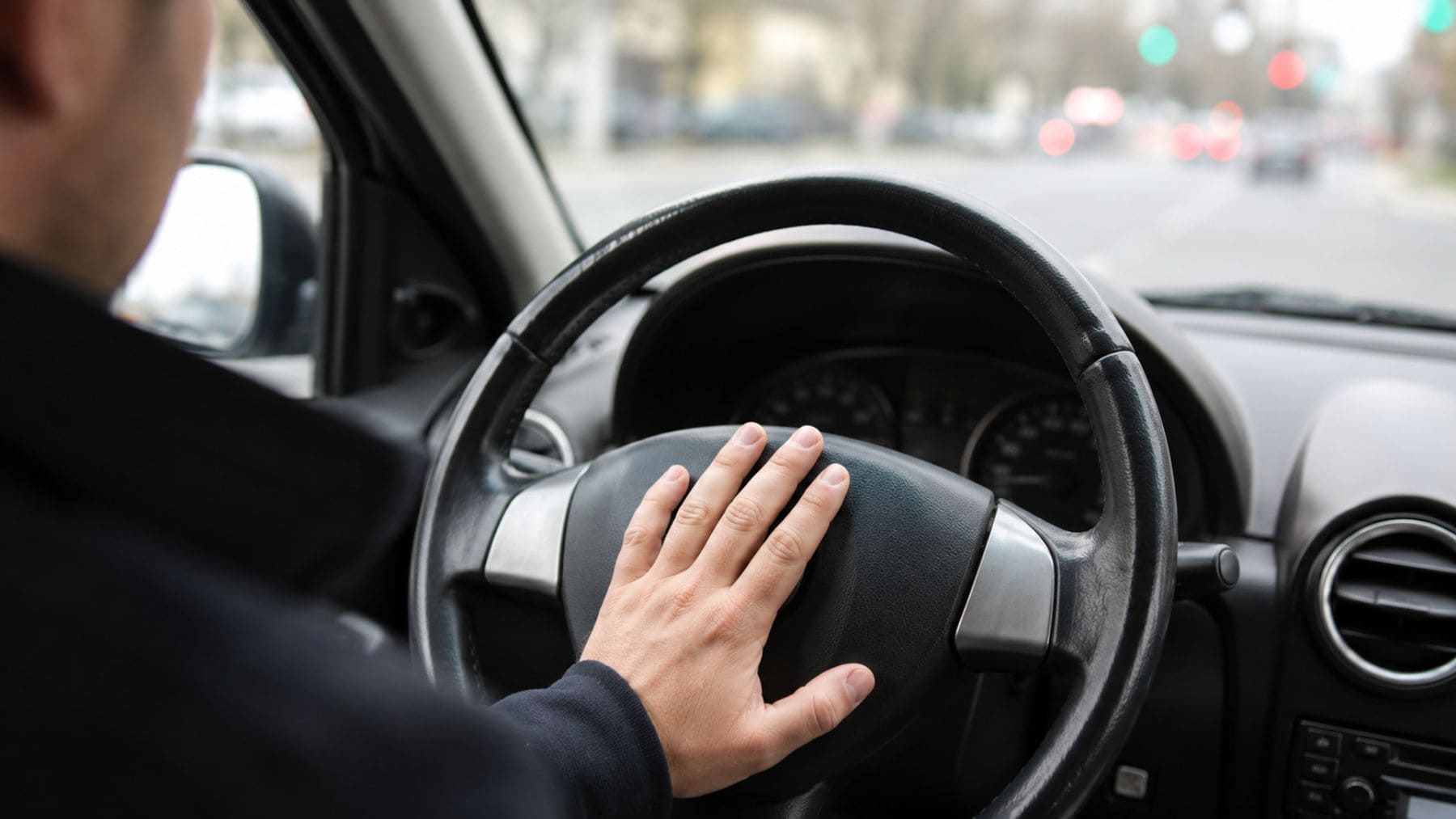 Conductor tocando el claxon del volante, una acción que la DGT puede sancionar con una multa de 80 euros si no existe un motivo reglamentario.