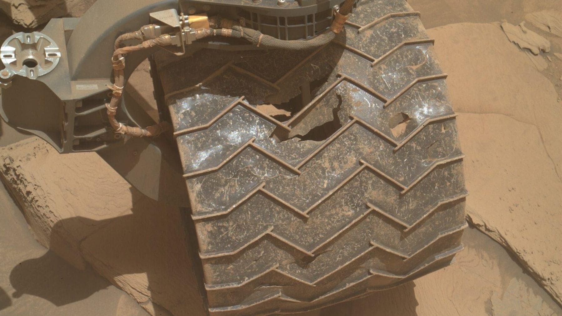 Rueda dañada del rover Curiosity de la NASA en Marte con grietas y un gran agujero provocado por el desgaste.