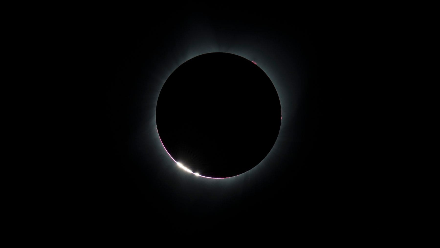 Perlas de Baily durante un eclipse solar total con la luz del Sol atravesando los valles de la Luna