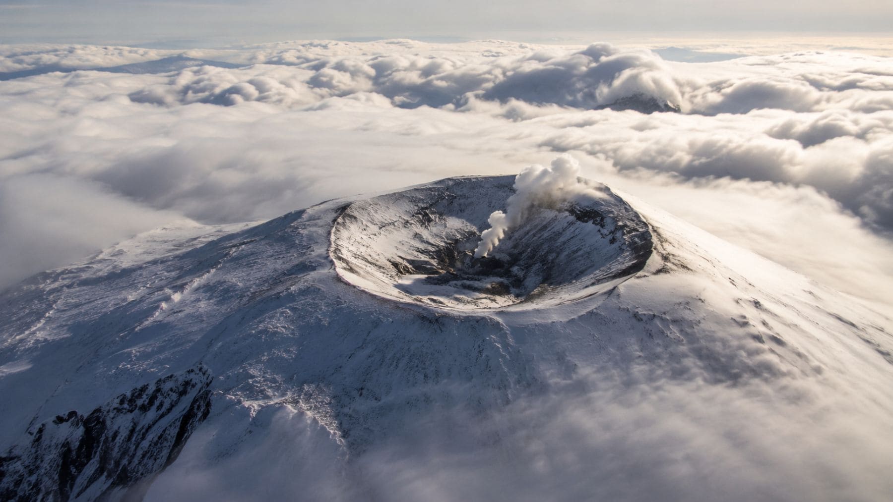 Vista aérea del volcán Monte Erebus en la Antártida, con su cráter activo rodeado de hielo y nieve, conocido por emitir partículas microscópicas de oro.