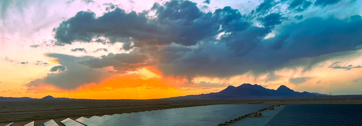 Paneles solares al atardecer bajo un cielo con nubes