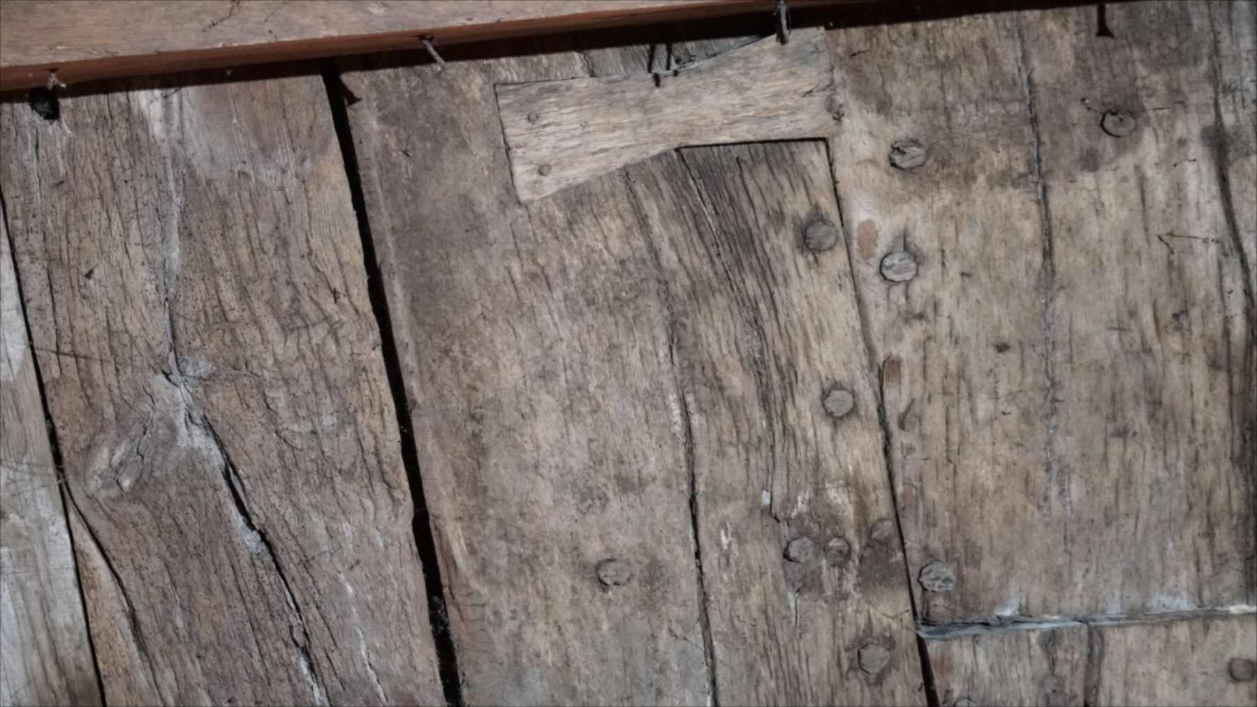 Tablones de madera del techo de un sótano de Constanza con hileras de clavos y una pieza de reparación del antiguo barco