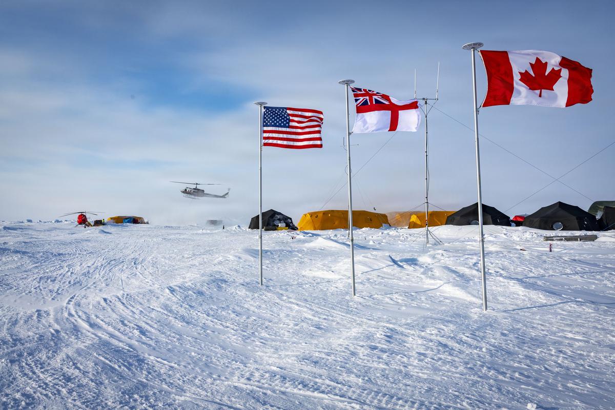 Campamento temporal de la Armada estadounidense sobre el hielo ártico durante Ice Camp 2026, con banderas, tiendas y un helicóptero