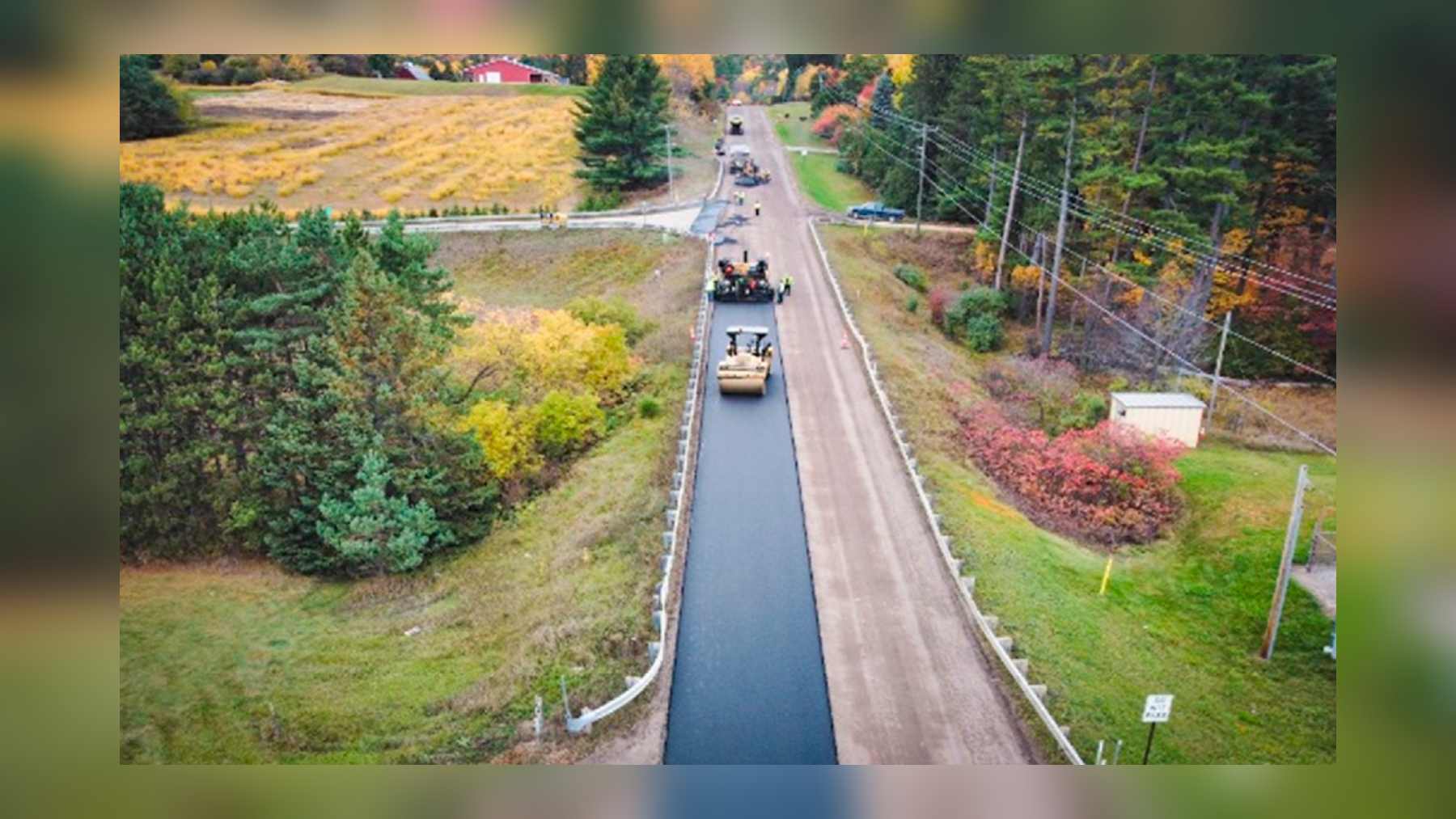 Obras de asfalto con vidrio reciclado en una carretera del condado de Dickinson, Michigan, con una apisonadora sobre la capa de nivelación
