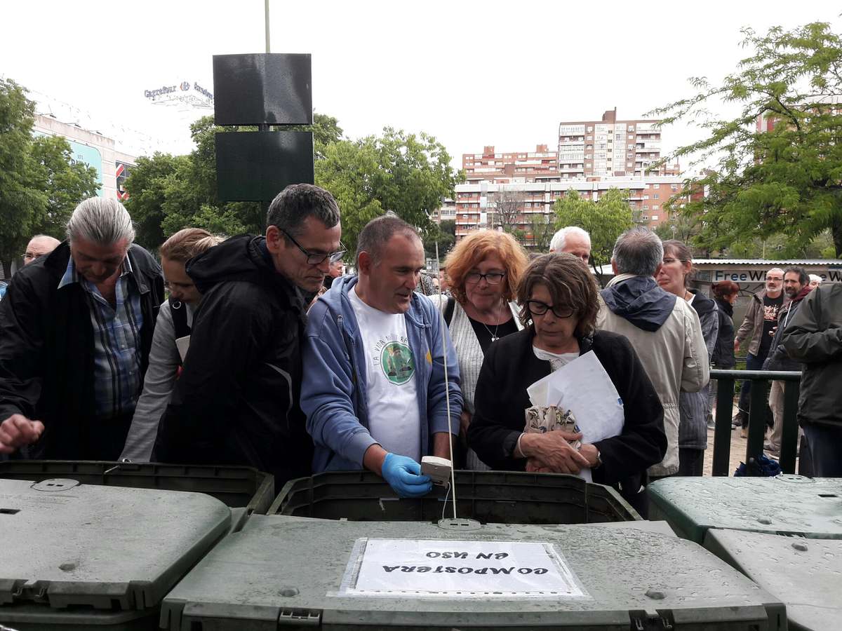 Personas junto a los compostadores de la primera área de compostaje comunitario de Madrid, en Hortaleza, el día de su inauguración