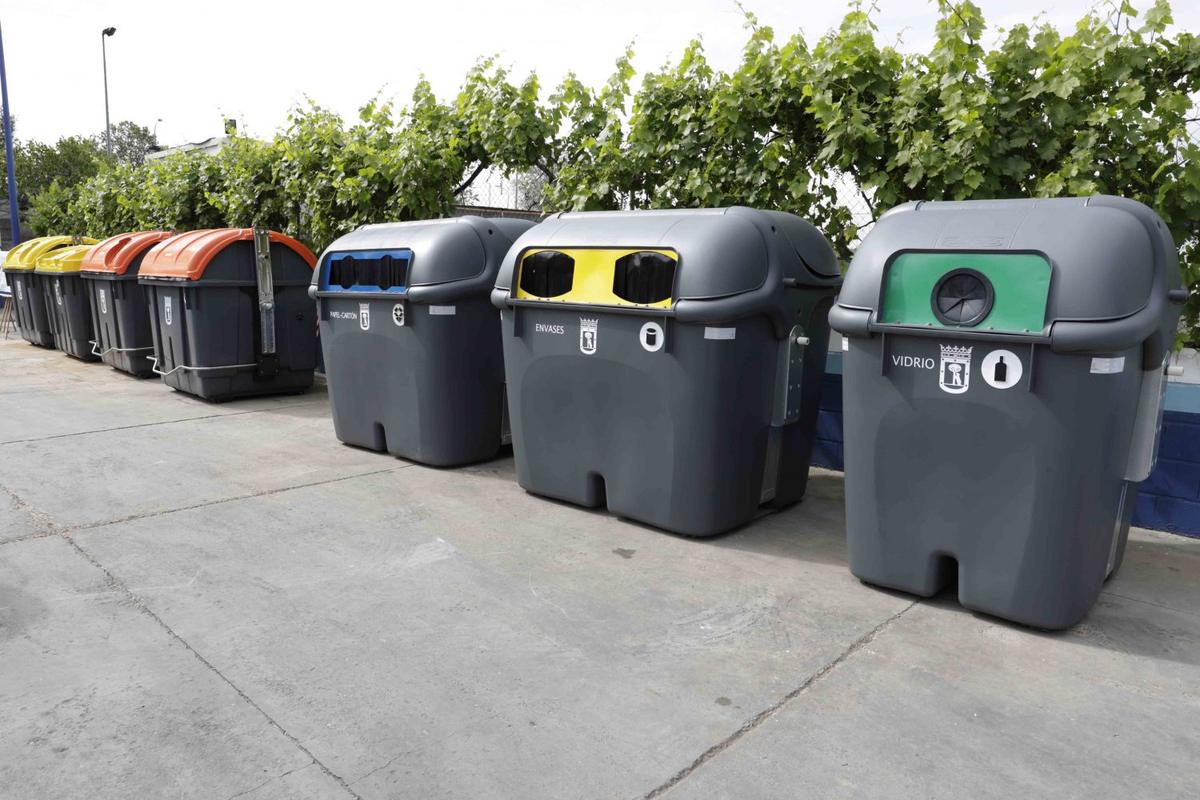 Fila de contenedores municipales de envases, vidrio y otras fracciones con el escudo del Ayuntamiento de Madrid