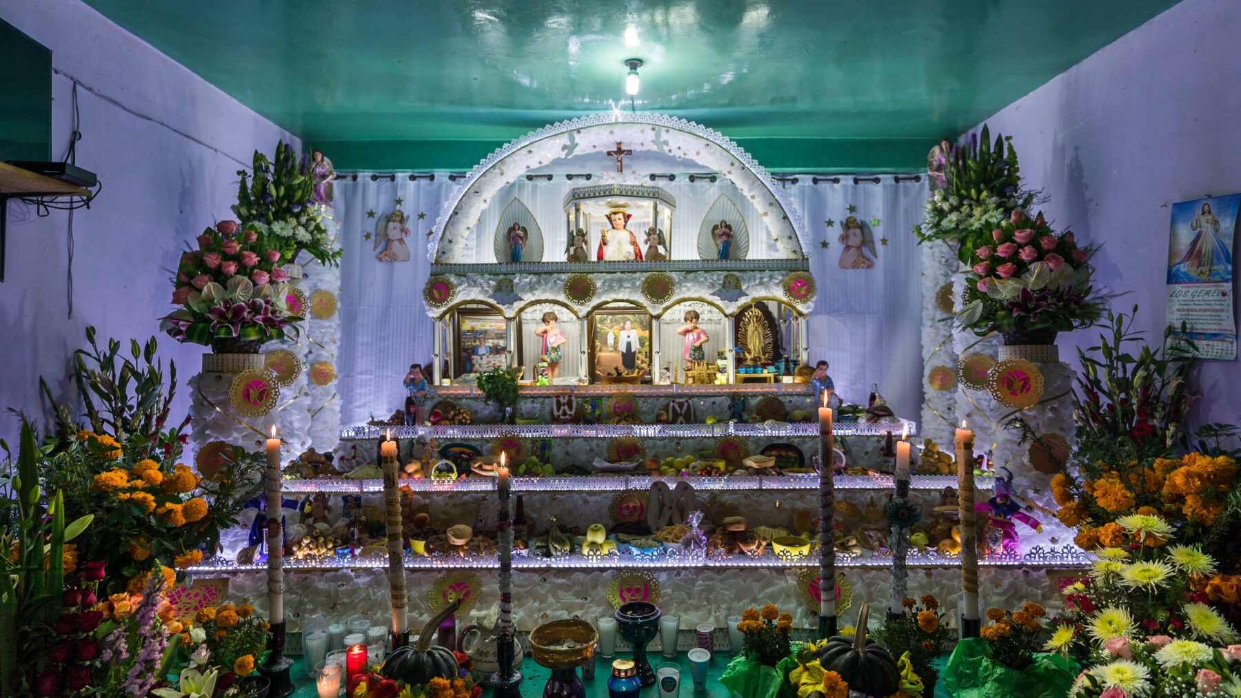Altar de ofrenda del Día de Muertos con flores de cempasúchil, velas e imágenes religiosas