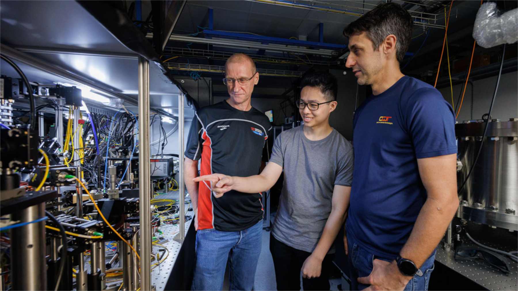 Murray Barrett y dos miembros de su equipo junto al montaje experimental del reloj atómico de lutecio en Singapur