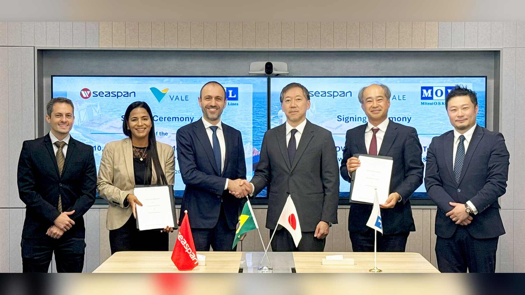 Ceremonia de firma de MOL y Vale para dos mineraleros con etanol: seis personas posan ante pantallas con los logotipos de las empresas
