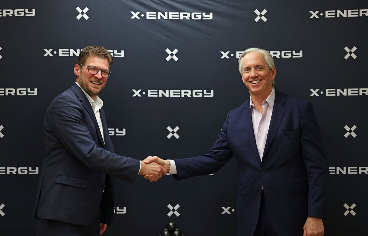 Representantes de SGL Carbon y X-energy se dan la mano ante un panel con el logotipo de X-energy