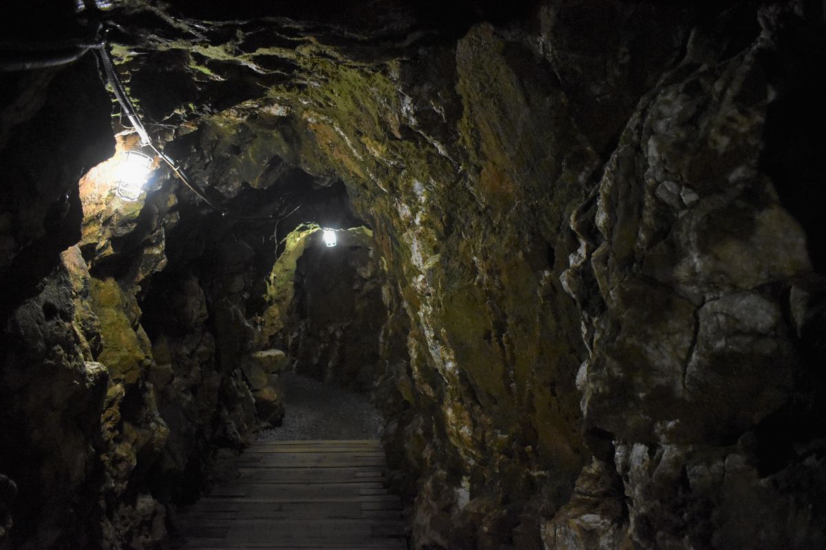 Galería subterránea restaurada de Reed Gold Mine con paredes de roca, lámparas y pasarela de madera