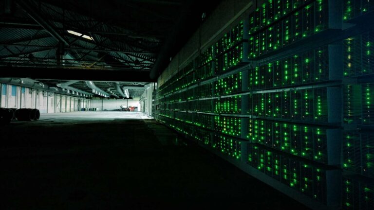 Granja de minería con filas de equipos encendidos, ligada a la huella hídrica de bitcoin