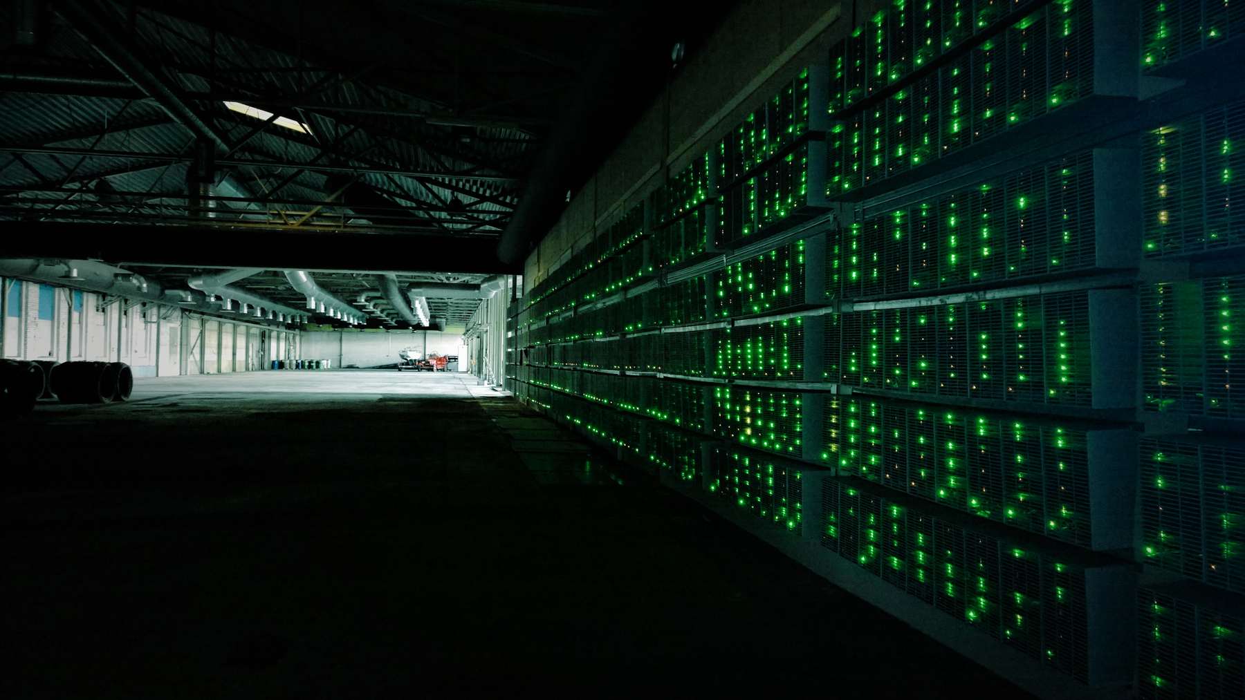 Granja de minería con filas de equipos encendidos, ligada a la huella hídrica de bitcoin
