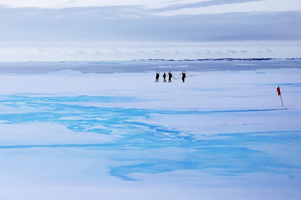 Superficie del glaciar Langhovde cubierta de agua de deshielo y lluvia en enero de 2022, con varias personas al fondo