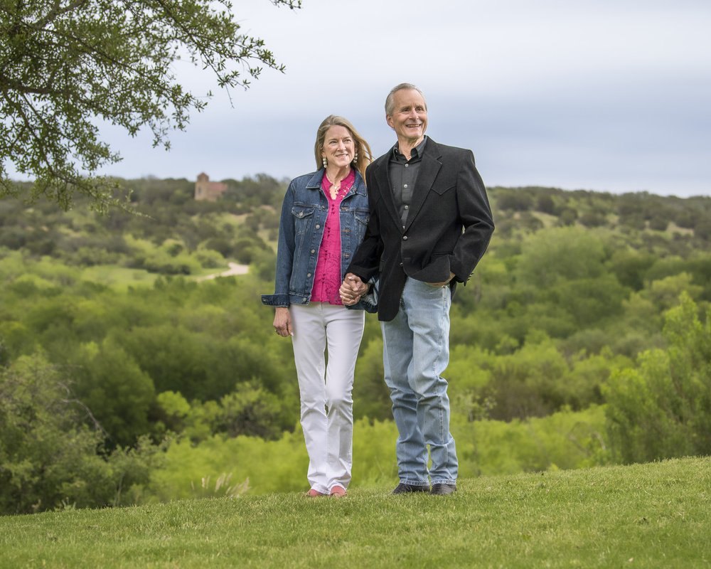 Mike y Mary Terry, propietarios del rancho de Texas MT7, de pie sobre la hierba con el monte al fondo