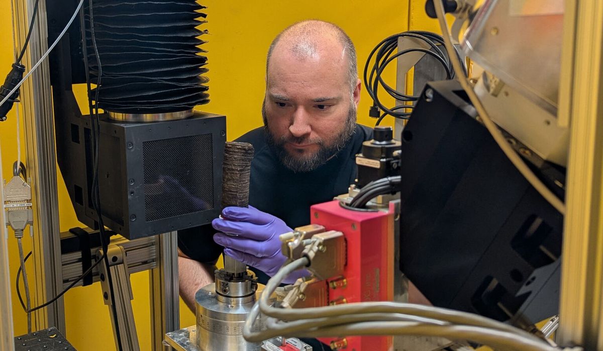 El físico del NIST Jacob LaManna coloca la réplica de papiro carbonizado en el equipo de tomografía de rayos X