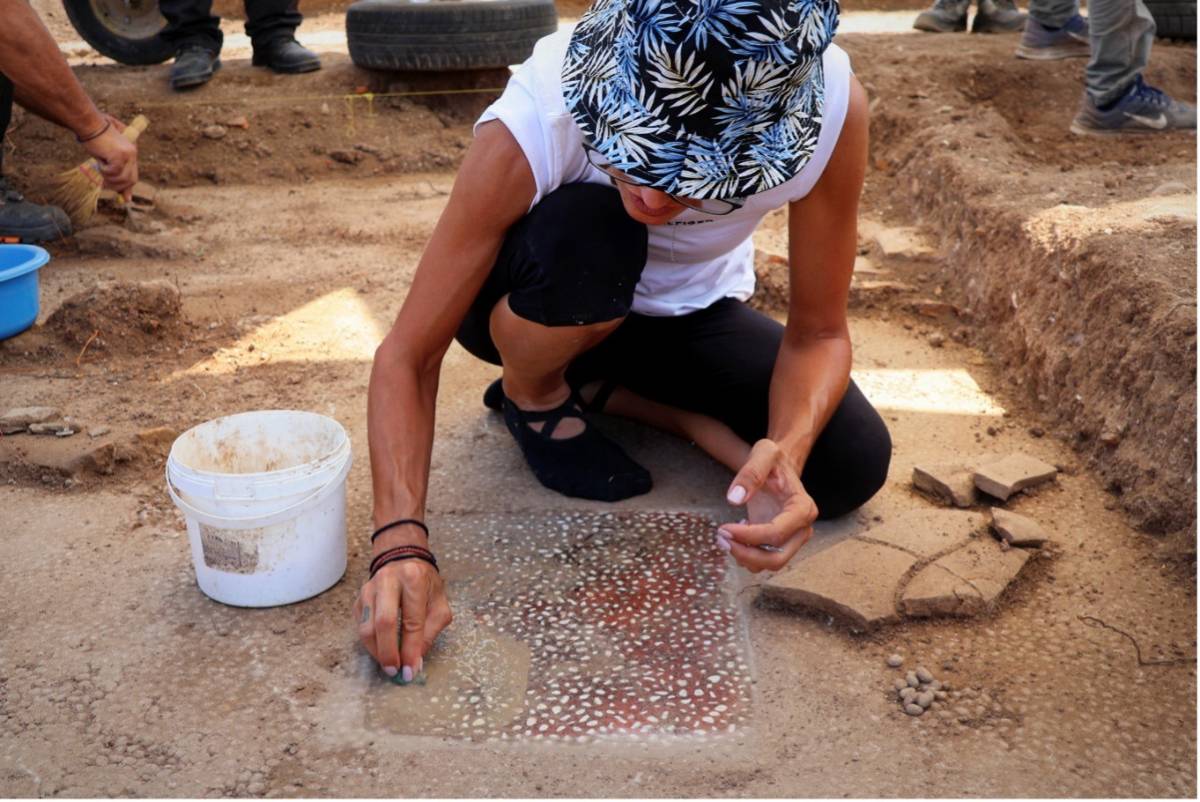 Una arqueóloga limpia un mosaico de teselas en las excavaciones de Mieza