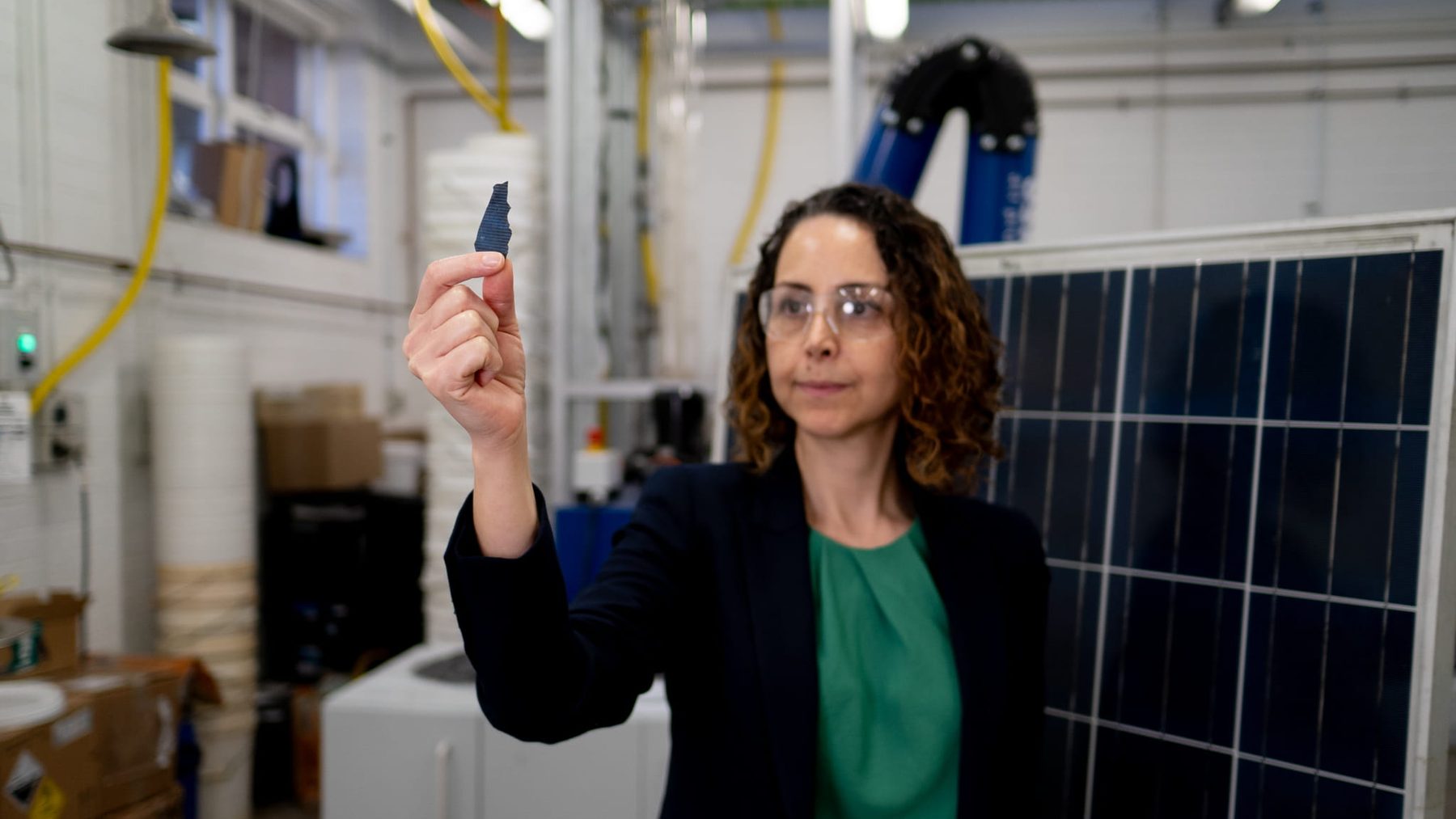 La investigadora Mahshid Firouzi sostiene un fragmento de material del que se recupera la plata de las células solares, junto a un panel solar