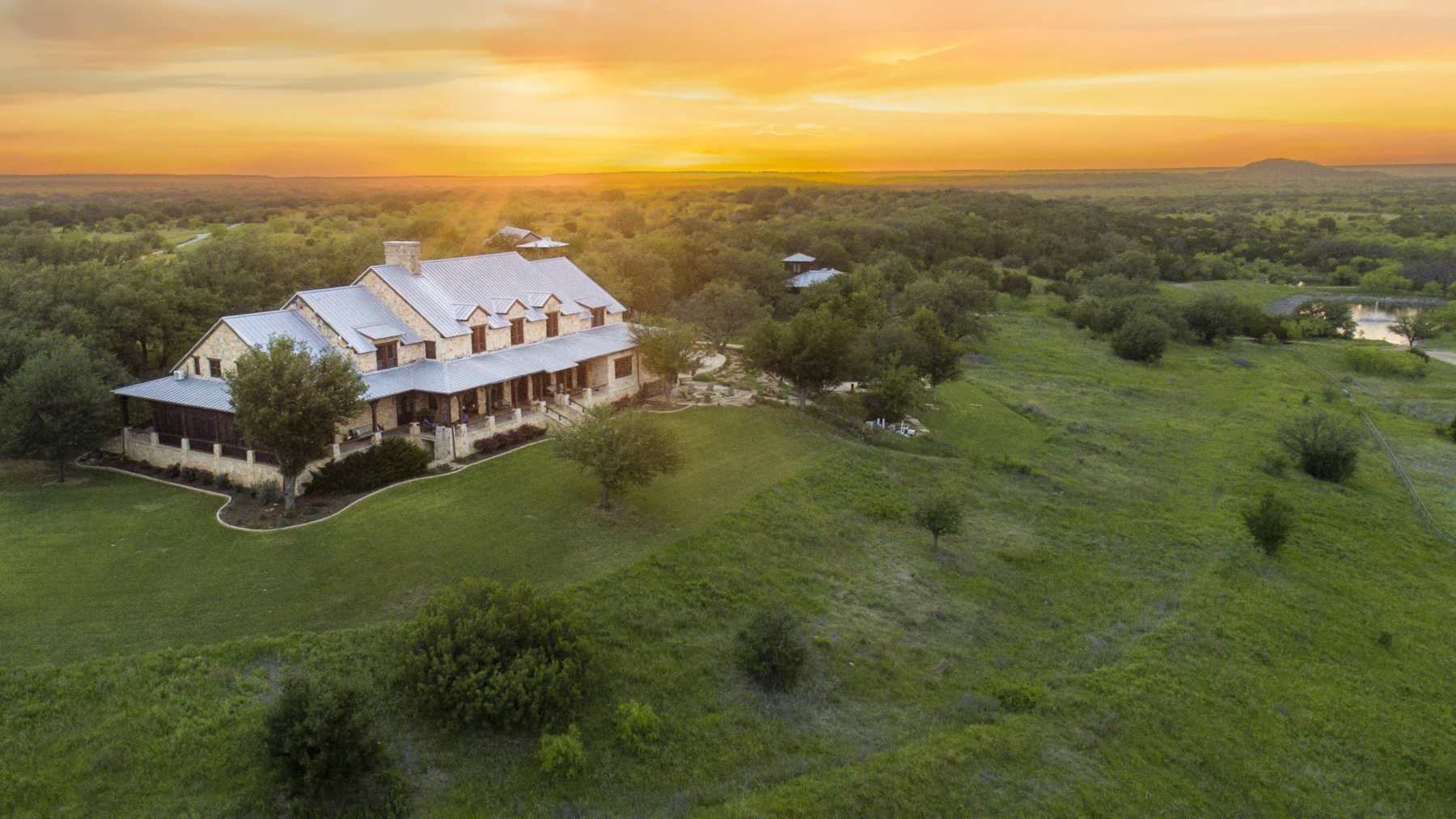 Vista aérea del rancho de Texas MT7 al amanecer, con la casa principal entre pastos y arboledas