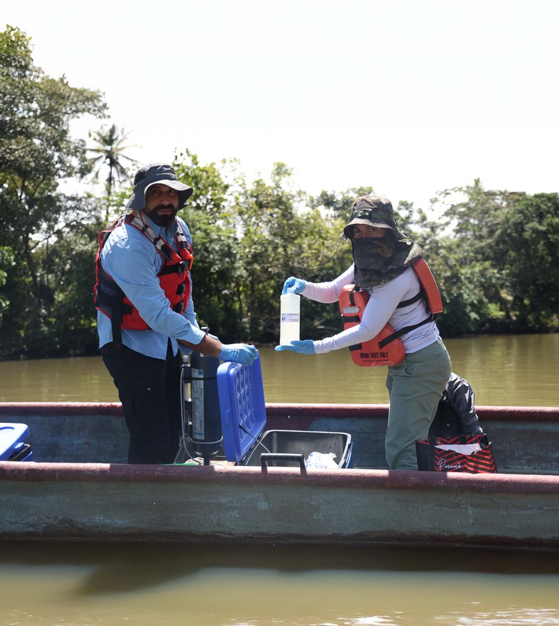 Técnicos toman una muestra de agua desde una lancha para los estudios ambientales del lago de Río Indio
