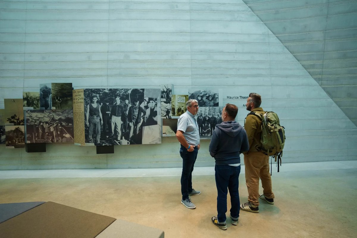 Visitantes ante el panel de fotografías históricas de los descubridores de Lascaux en Lascaux IV