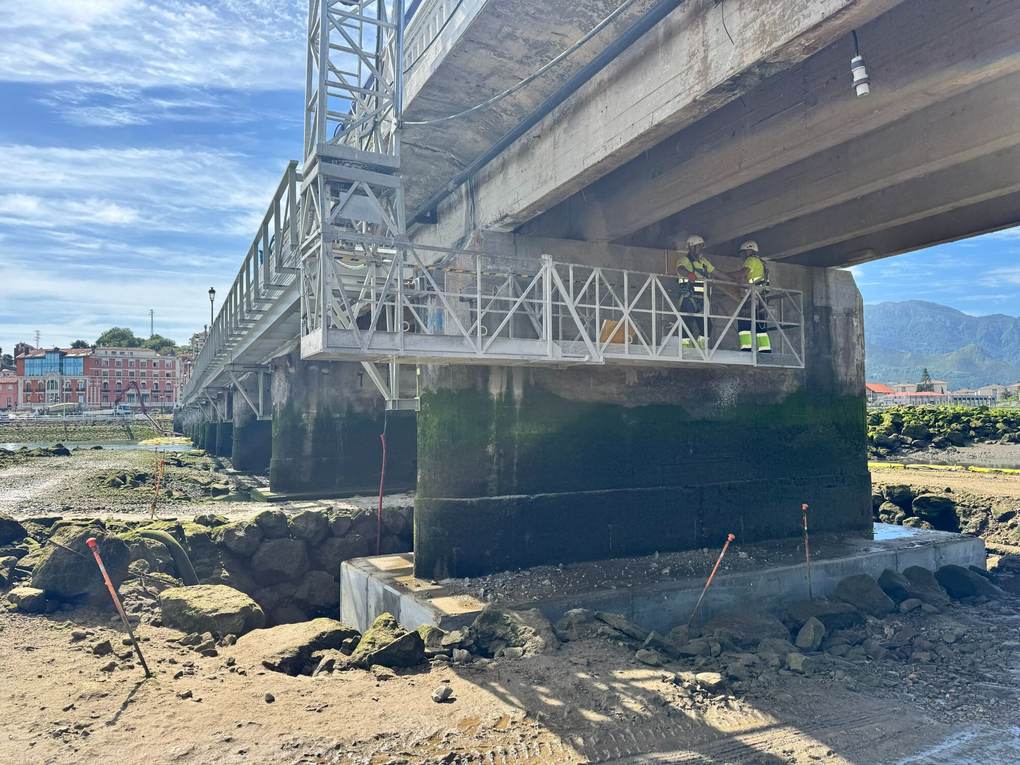 Pila del puente de Ribadesella con una base de hormigón nueva y una plataforma de andamio colgada del tablero con dos operarios