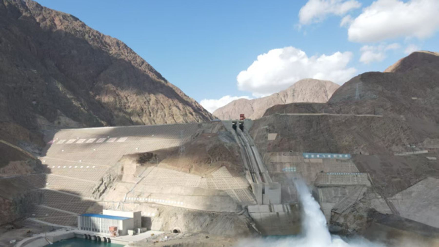 Vista de la presa de Dashixia, en el río Kumarak (Xinjiang), con el aliviadero vertiendo agua entre montañas áridas