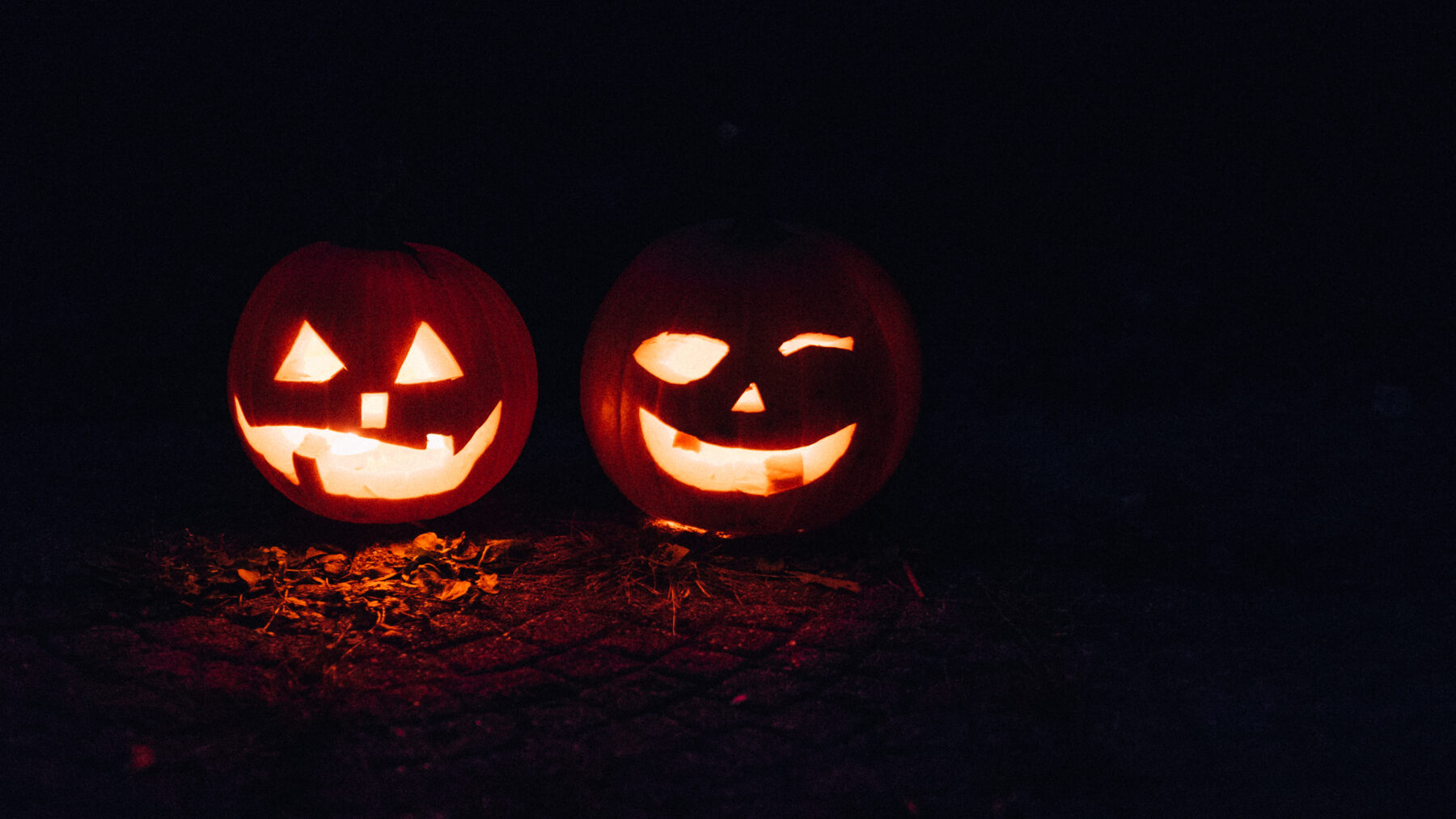 Dos calabazas talladas e iluminadas por dentro en la noche de Halloween