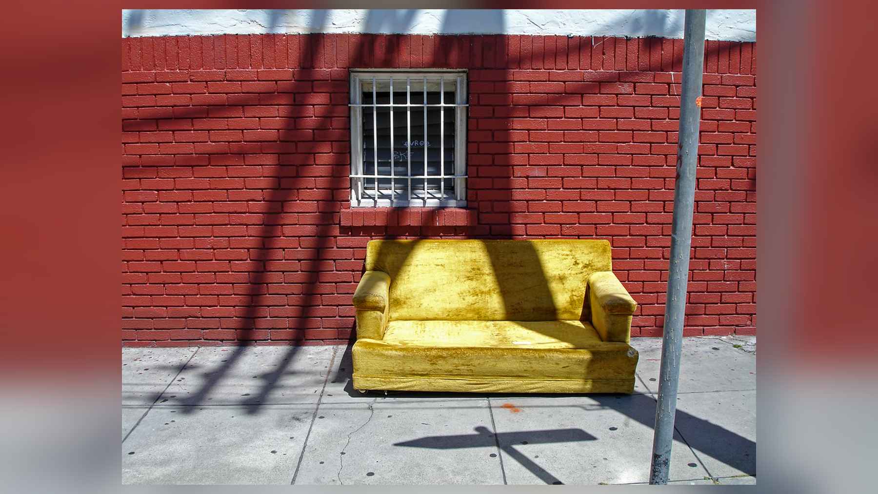 Sofá amarillo abandonado en una acera de San Francisco, un ejemplo del problema del reciclaje de muebles en Estados Unidos