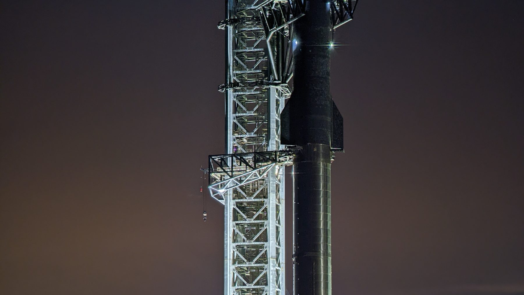 Cohete Starship de SpaceX junto a la torre de lanzamiento de Starbase, en Texas, al atardecer
