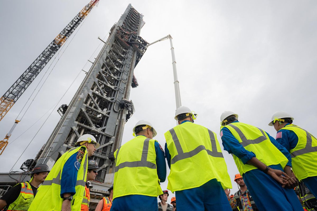 Astronautas de Artemis III con chalecos y cascos ante la torre de lanzamiento de Starship en el complejo 39A