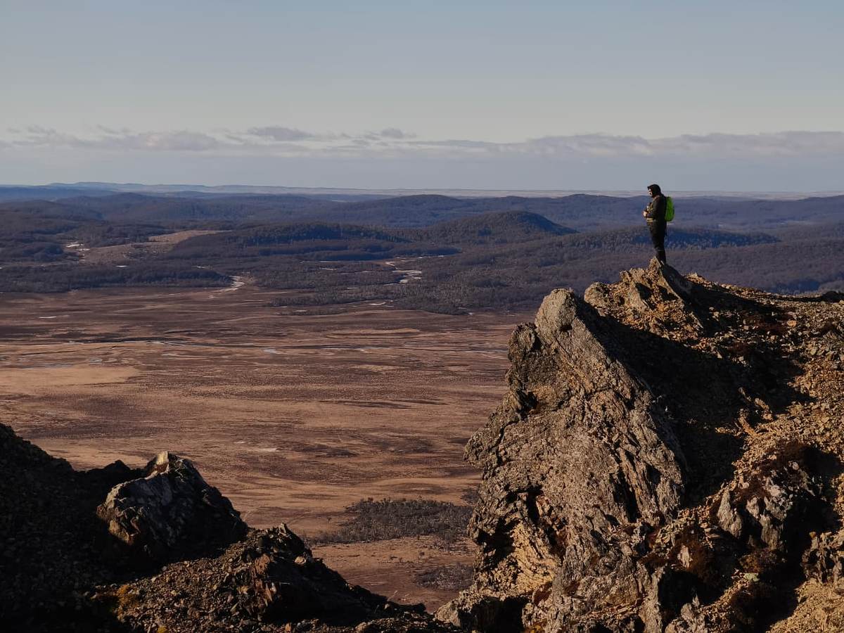 Una persona observa un amplio valle del Parque Karukinka desde un afloramiento rocoso